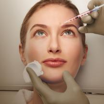 Close-up of a woman's face receiving an injectionin her forehead